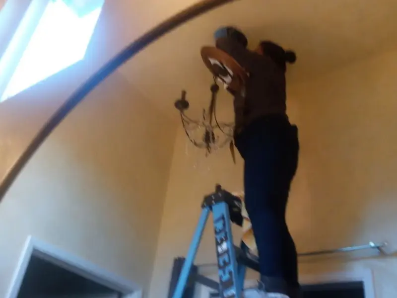 Electrician installing a chandelier in a Saginaw residence